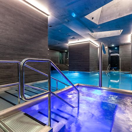 แกรนด์โฮเต็ล พัปป์ Hotel การ์โลวีวารี ภายนอก รูปภาพ The photo shows a modern spa area with a pool. There are sleek, dark walls and blue lighting that creates a tranquil atmosphere. A metal railing leads down into the pool, which has a section with bubbling water. The overall design features clean line
