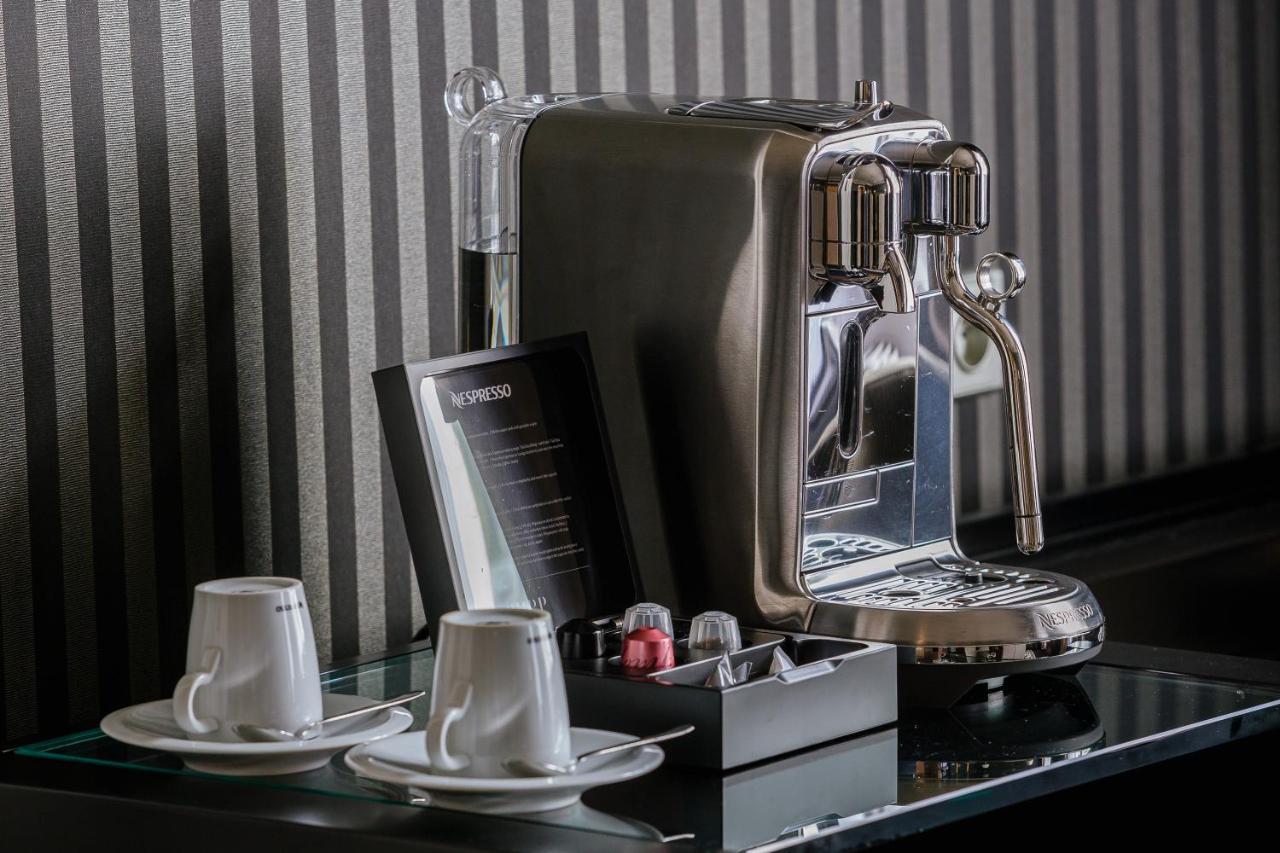 แกรนด์โฮเต็ล พัปป์ Hotel การ์โลวีวารี ภายนอก รูปภาพ The photo shows a sleek, modern coffee machine positioned on a countertop. The machine has a shiny, metallic finish and is equipped with a faucet for dispensing coffee. Next to the coffee machine, there are two white coffee cups on small saucers. In 