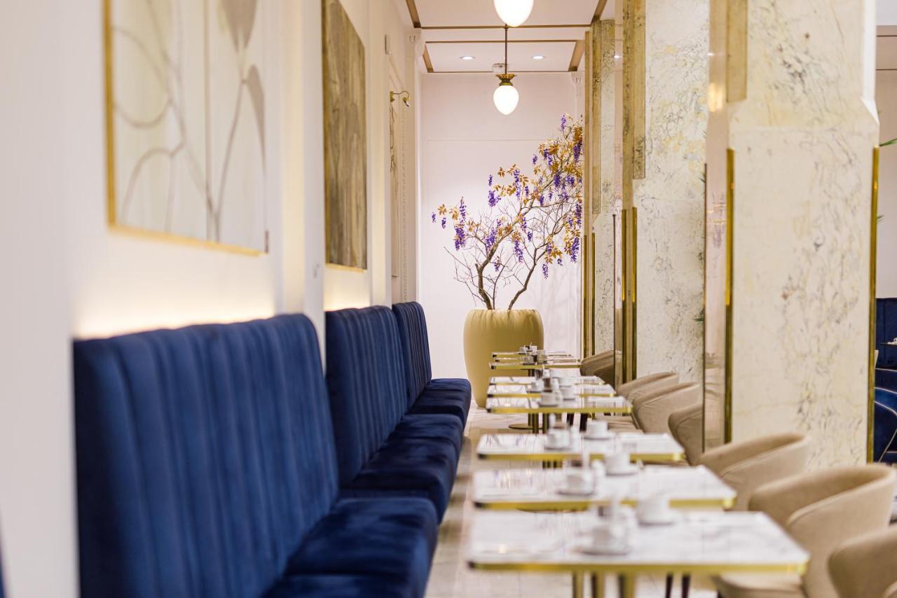 แกรนด์โฮเต็ล พัปป์ Hotel การ์โลวีวารี ภายนอก รูปภาพ The photo shows a stylish and elegant interior of a café or restaurant. On one side, there are long, plush blue benches against the walls, providing seating for guests. The tables are set with white plates and cutlery, suggesting a careful arrangemen