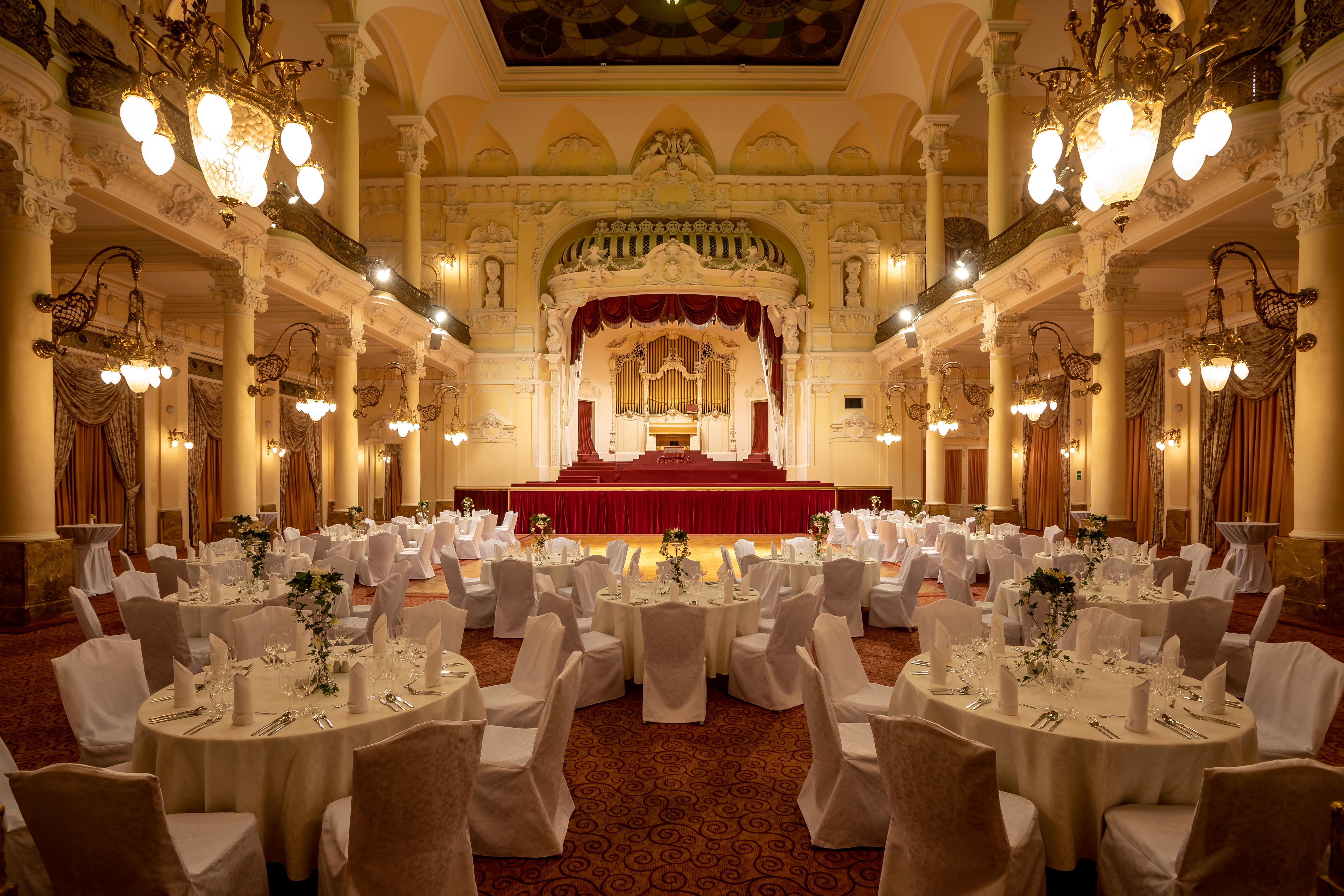 แกรนด์โฮเต็ล พัปป์ Hotel การ์โลวีวารี ภายนอก รูปภาพ The photo depicts an elegantly decorated banquet hall. The room features several round tables, each covered with white tablecloths and adorned with floral arrangements. Surrounding the tables are chairs, also draped in white fabric. 

The venue is ch