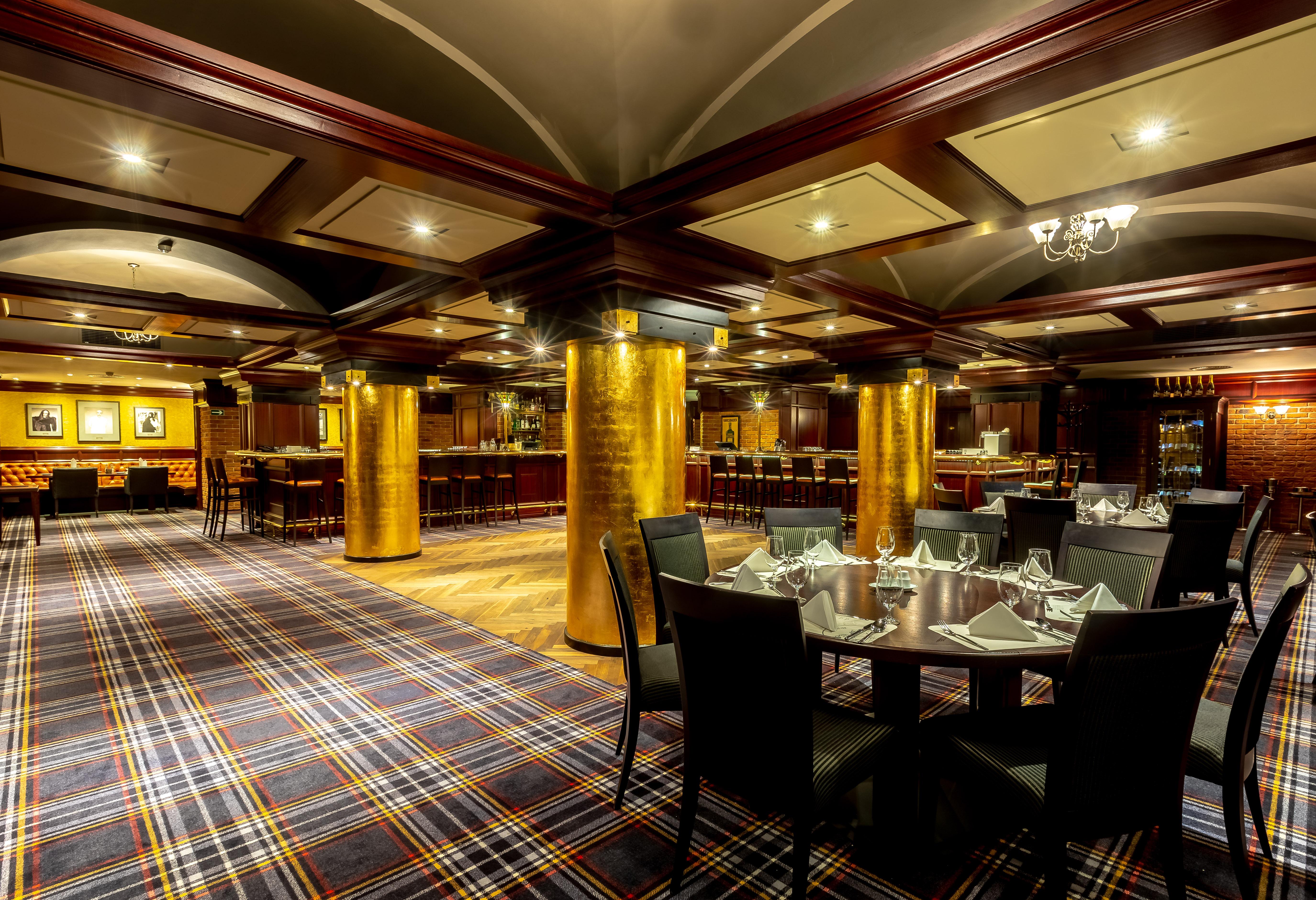 แกรนด์โฮเต็ล พัปป์ Hotel การ์โลวีวารี ภายนอก รูปภาพ The photo shows an elegant dining area in a restaurant. The interior features a modern design with a checkered carpet and wooden accents. Golden columns are prominent in the space, adding a touch of luxury. The tables are set with neat tableware, and