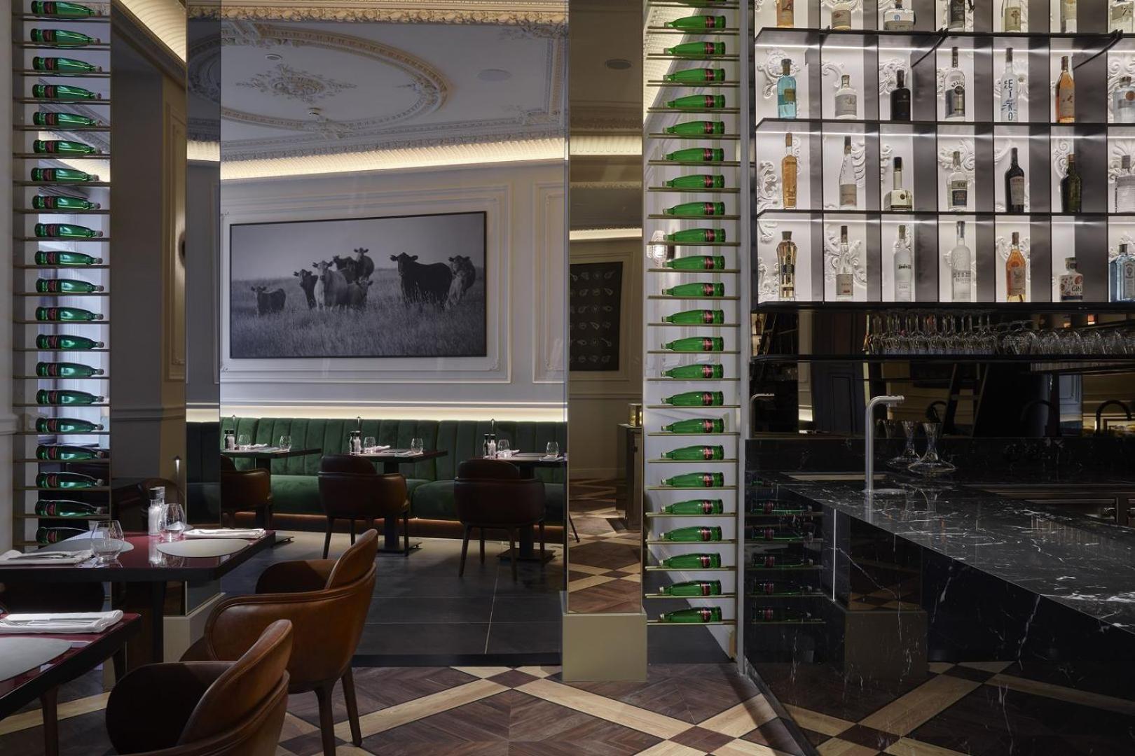 แกรนด์โฮเต็ล พัปป์ Hotel การ์โลวีวารี ภายนอก รูปภาพ The photo shows the interior of a stylish restaurant. There is a large photograph of cows on the wall, adding a rustic touch to the decor. The space features elegant seating with dark brown chairs, and the tables are set for dining. A bar area is vis