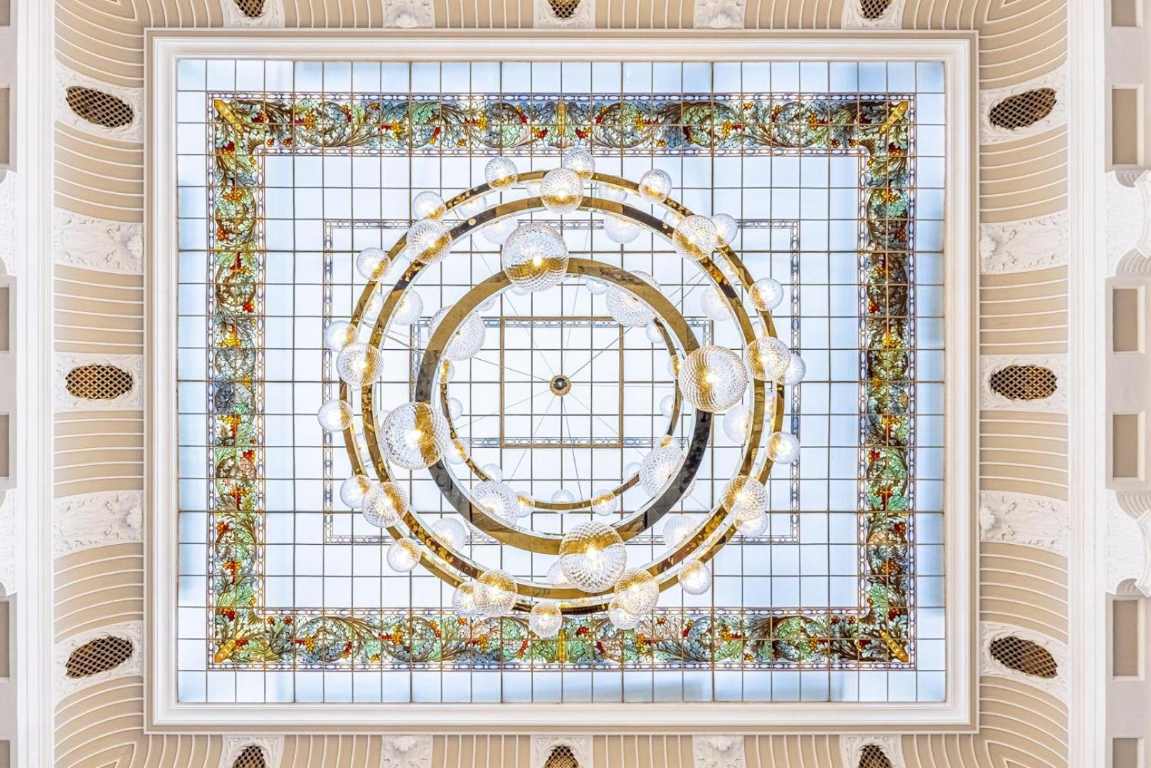 แกรนด์โฮเต็ล พัปป์ Hotel การ์โลวีวารี ภายนอก รูปภาพ The photo depicts an ornate ceiling design featuring a central circular lighting fixture surrounded by a decorative frame. The frame is embellished with intricate patterns and colors, possibly including floral or geometric motifs. The outer edges sho