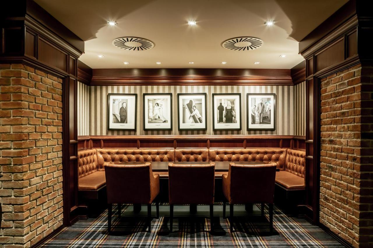 แกรนด์โฮเต็ล พัปป์ Hotel การ์โลวีวารี ภายนอก รูปภาพ The photo shows an elegantly designed room, likely a private dining or meeting area. It features a circular seating arrangement with a table surrounded by plush, brown leather chairs. The walls are adorned with a combination of exposed brick and stri